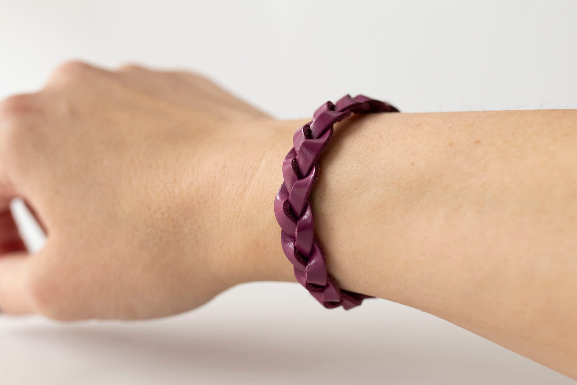 Purple braided bracelet on a wrist against a white background