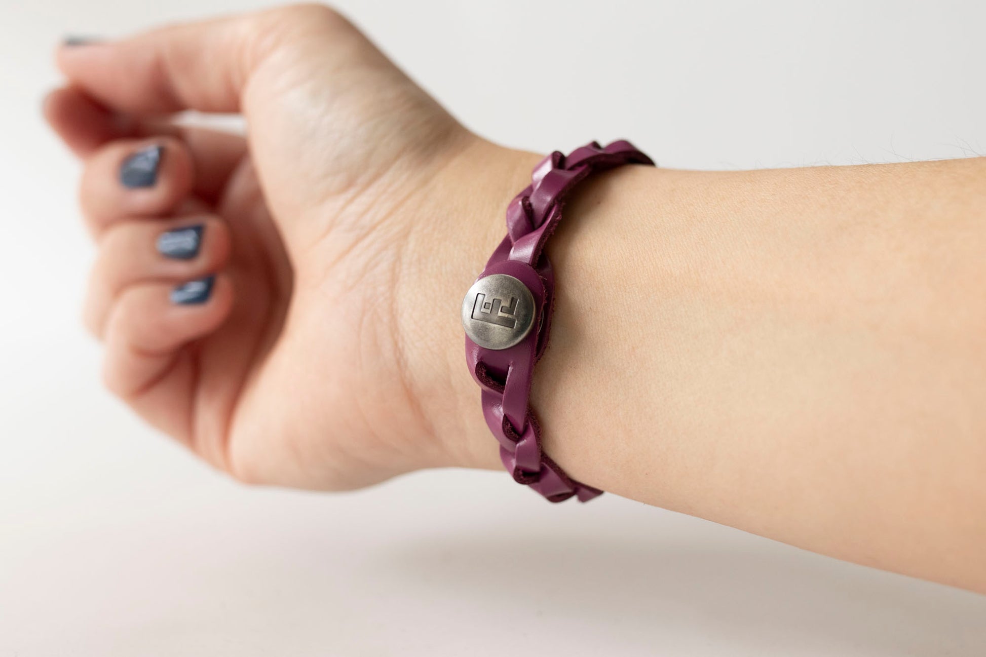 Purple bracelet with a circular emblem on a wrist against a light background