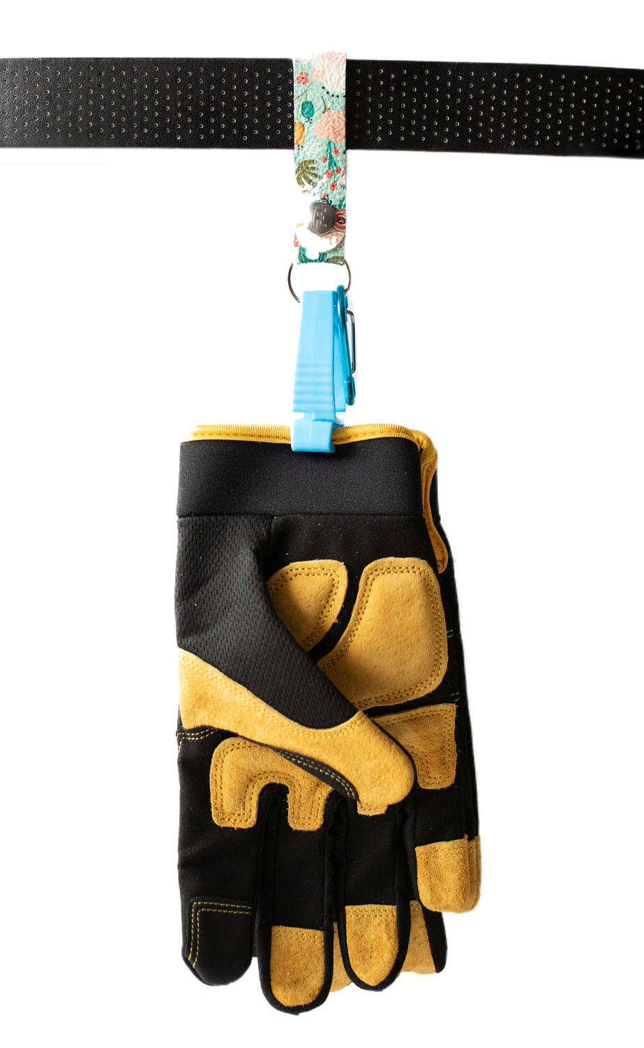 A black and tan work glove hanging from a black strap with a floral-patterned lanyard and blue clip, isolated on a white background.